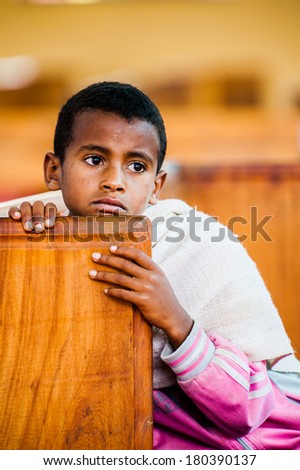 AKSUM, ETHIOPIA - SEPTEMBER 24, 2011: Unidentified Ethiopian boy thinks of something holding the wood. People in Ethiopia suffer of poverty due to the unstable situation