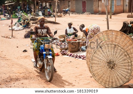 PORTO-NOVO, BENIN - MAR 9, 2012: Unidentified Beninese woman goes shopping on a local market on a motorbike. People of Benin suffer of poverty due to the difficult economic situation.