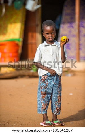 PORTO-NOVO, BENIN - MAR 9, 2012: Unidentified Beninese little boy with a apple at the market. People of Benin suffer of poverty due to the difficult economic situation.