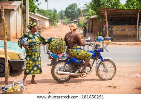 PORTO-NOVO, BENIN - MAR 9, 2012: Unidentified Beninese woman goes to the market on a motor bike. People of Benin suffer of poverty due to the difficult economic situation.