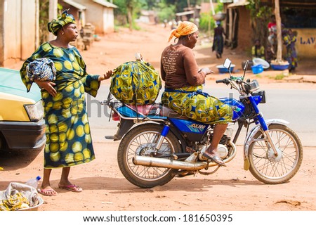 PORTO-NOVO, BENIN - MAR 9, 2012: Unidentified Beninese woman goes to the market on a motor bike. People of Benin suffer of poverty due to the difficult economic situation.