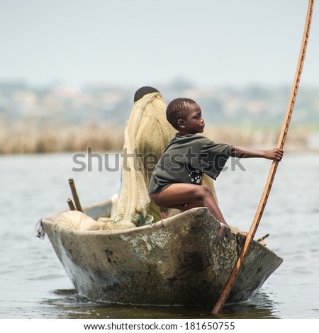 PORTO-NOVO, BENIN - MAR 9, 2012: Unidentified Beninese man and little boy work as a team to get fish. People of Benin suffer of poverty due to the difficult economic situation.