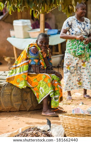 PORTO-NOVO, BENIN - MAR 9, 2012: Unidentified Beninese woman in a colorful dress sits and thinks of something. People of Benin suffer of poverty due to the difficult economic situation.