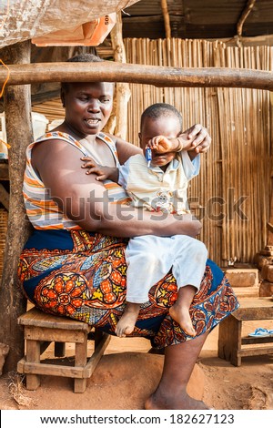 PORTO-NOVO, BENIN - MAR 9, 2012: Unidentified Beninese fat smiling woman plays with her little son in the market. People of Benin suffer of poverty due to the difficult economic situation.