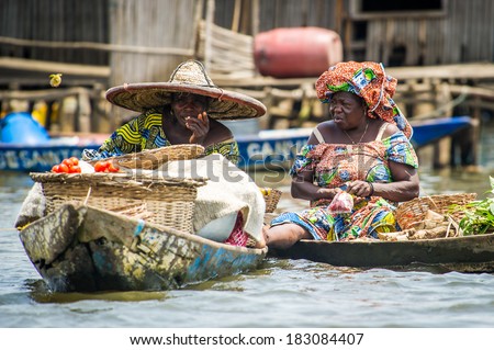 PORTO-NOVO, BENIN - MAR 9, 2012: Unidentified Beninese  women transport food in a wooden boat. People of Benin suffer of poverty due to the difficult economic situation.
