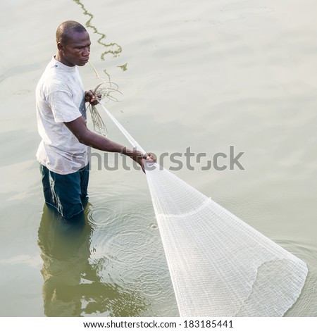 PORTO-NOVO, BENIN - MAR 9, 2012: Unidentified Beninese man puts a fishing net into the water. People of Benin suffer of poverty due to the difficult economic situation