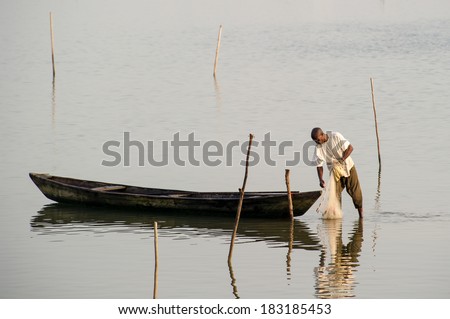 PORTO-NOVO, BENIN - MAR 9, 2012: Unidentified Beninese man puts a fishing net into the water. People of Benin suffer of poverty due to the difficult economic situation