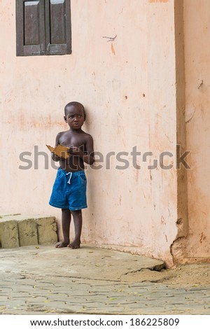 PORTO-NOVO, BENIN - MAR 10, 2012: Unidentified Beninese boy stays at the house corner. People of Benin suffer of poverty due to the difficult economic situation