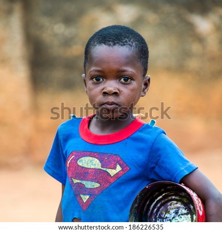 PORTO-NOVO, BENIN - MAR 10, 2012: Unidentified Beninese boy in a Superman shirt with a can. People of Benin suffer of poverty due to the difficult economic situation