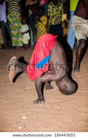 LOME, TOGO - MAR 7, 2012: Unidentified Togolese boy in red shorts show acrabatic tricks during the fire show performance. People in Togo suffer of poverty due to a difficult economical situation