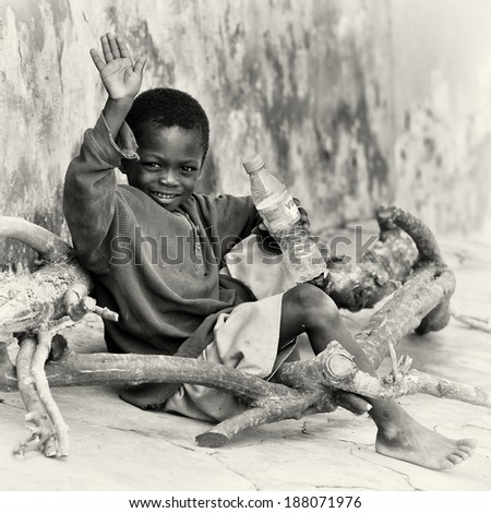 ACCRA, GHANA - MAR 5, 2012: Unidentified Ghanaian boy sits with a bottle of water sits in the street. People of Ghana suffer of poverty due to the difficult economic situation