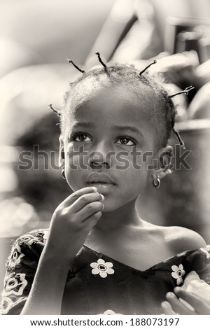 ACCRA, GHANA - MAR 4, 2012: Unidentified Ghanaian girl eats a candy in the street. People of Ghana suffer of poverty due to the difficult economic situation