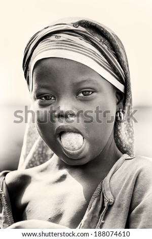 ACCRA, GHANA - MAR 5, 2012: Unidentified Ghanaian girl with a white paste on her tongue. People of Ghana suffer of poverty due to the difficult economic situation