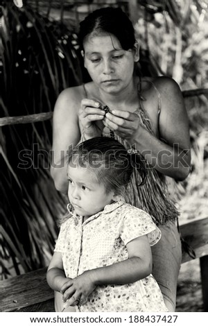 AMAZONIA, PERU - NOV 10, 2010: Unidentified Amazonian woman and her daughter. Indigenous people of Amazonia are protected by COICA (Coordinator of Indigenous Organizations of the Amazon River Basin)