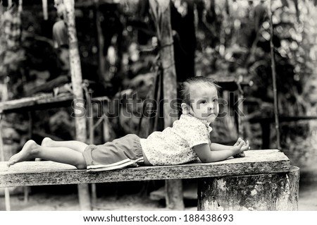 AMAZONIA, PERU - NOV 10, 2010: Unidentified Amazonian young girl on a bench. Indigenous people of Amazonia are protected by  COICA (Coordinator of Indigenous Organizations of the Amazon River Basin)