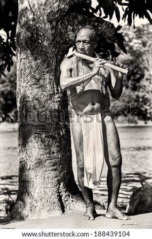 EMBERA VILLAGE, PANAMA, JANUARY 9, 2012: Unidentified native Indian man play the fife of wood near the tree. Indian reservation is the way to conserve native culture, language, traditions