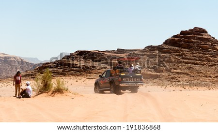 WADI RUM, JORDAN - APR 30, 2014: Mitsubishi jeep with the tourists in the desert of Wadi Rum. Wadi Rum valley is the UNESCO World Heritage site