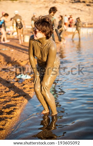DEAD SEA RESORT, JORDAN - APR 30, 2014: Unidentified Chinese girl poses in the mud of the Dead Sea. Dead Sea mud posesses the medical qualities and helps to the people with skin problems