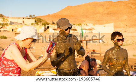 DEAD SEA RESORT, JORDAN - APR 30, 2014: Unidentified Chinese tourists in the mud of the Dead Sea. Dead Sea mud posesses the medical qualities and helps to the people with skin problems