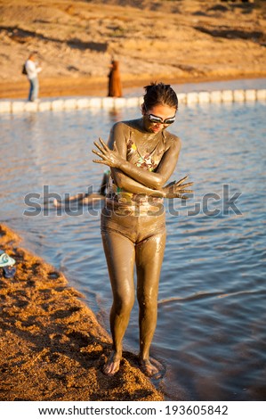 DEAD SEA RESORT, JORDAN - APR 30, 2014: Unidentified Chinese girl poses in the mud of the Dead Sea. Dead Sea mud posesses the medical qualities and helps to the people with skin problems