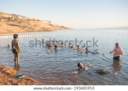 DEAD SEA RESORT, JORDAN - APR 30, 2014: Unidentified Chinese people in the mud of the Dead Sea. Dead Sea mud posesses the medical qualities and helps to the people with skin problems