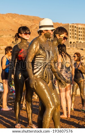DEAD SEA RESORT, JORDAN - APR 30, 2014: Unidentified Chinese tourists pose in the mud of the Dead Sea. Dead Sea mud posesses the medical qualities and helps to the people with skin problems