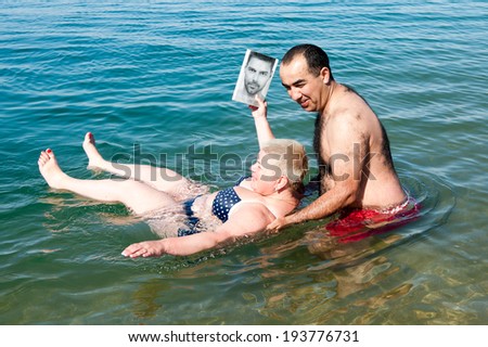 DEAD SEA RESORT, JORDAN - MAY 1, 2014: Unidentified man helps his wife to get out of the salty water of the Dead Sea. Dead Sea water is used for medical purposes for the people with skin problems