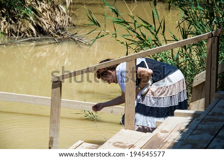 JESUS CHRIST BAPTISM SITE , ISRAEL - MAY 1, 2014: Unidentified woman near the Sacred water of the River Jordan. River where Jesus of Nazareth was baptized by John the Baptist.