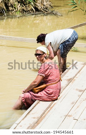 JESUS CHRIST BAPTISM SITE , ISRAEL - MAY 1, 2014: Unidentified women near the Sacred water of the River Jordan. River where Jesus of Nazareth was baptized by John the Baptist.