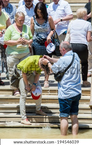 JESUS CHRIST BAPTISM SITE , ISRAEL - MAY 1, 2014: Unidentified man put the Sacred water of the River Jordan on an unidentified woman. River where Jesus of Nazareth was baptized by John the Baptist.