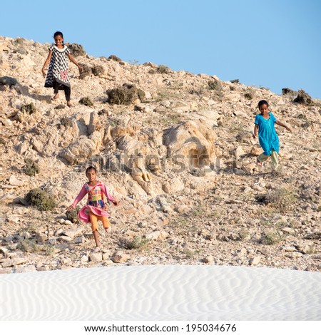 SOCOTRA, YEMEN - JAN 12, 2014: Unidentified Yemeni little children run down a hill to the beach of the Island of Socotra. Children in Socotra live in poverty and grow without education