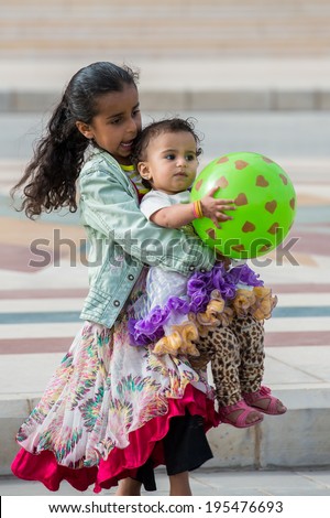 SANA'A, YEMEN - JAN 11, 2014: Unidentified Yemeni little girl plays with a green rubber ball girl in the street in Sana'a. Children of Yemen grow up without education
