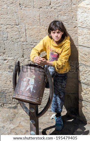 SANA\'A, YEMEN - JAN 11, 2014: Unidentified Yemeni little girl near the trash box in the street in Sana\'a. Children of Yemen grow up without education