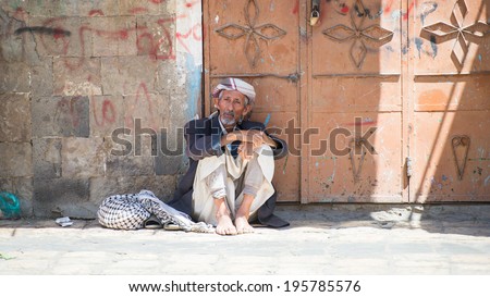 SANA\'A, YEMEN - JAN 11, 2014: Unidentified Yemeni old man sits in the street. People of Yemen suffer of poverty due to the unstable political and poor economical situation