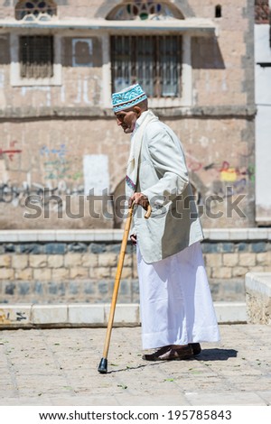 SANA'A, YEMEN - JAN 11, 2014: Unidentified Yemeni old man walks with a stick in the street. People of Yemen suffer of poverty due to the unstable political and poor economical situation