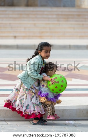 SANA'A, YEMEN - JAN 11, 2014: Unidentified Yemeni little girl plays with a green rubber ball girl in the street in Sana'a. Children of Yemen grow up without education