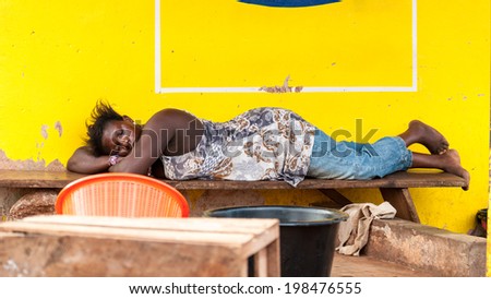 ACCRA, GHANA - MARCH 4, 2012: Unidentified Ghanaian woman sleeps on a bench in the street in Ghana. People of Ghana suffer of poverty due to the unstable economic situation