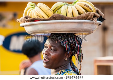 ACCRA, GHANA - MARCH 4, 2012: Unidentified Ghanaian woman carries bananas in the street in Ghana. People of Ghana suffer of poverty due to the unstable economic situation
