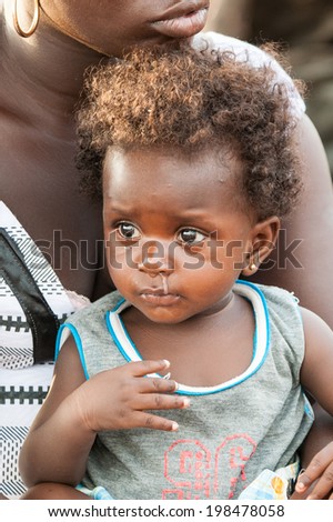 ACCRA, GHANA - MARCH 5, 2012: Unidentified Ghanaian baby boy on his mother lap in the street in Ghana. Children of Ghana suffer of poverty due to the unstable economic situation