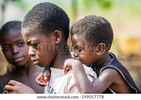 ACCRA, GHANA - MARCH 6, 2012: Unidentified Ghanaian boy carries his little brother on his back in the street in Ghana. Children of Ghana suffer of poverty due to the unstable economic situation