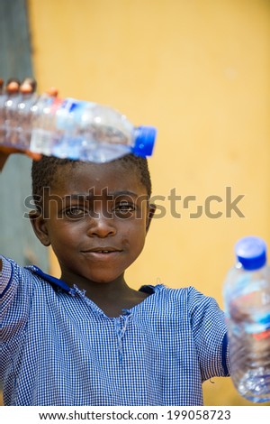 ACCRA, GHANA - MARCH 6, 2012: Unidentified Ghanaian boy with an empty bottle of water in the street in Ghana. Children of Ghana suffer of poverty due to the unstable economic situation