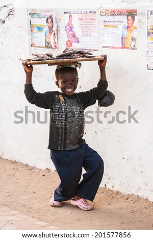 ACCRA, GHANA - MARCH 3, 2012: Unidentified Ghanaian smiling little boy offers to buy a fish in Ghana. People of Ghana suffer of poverty due to the unstable economic situation