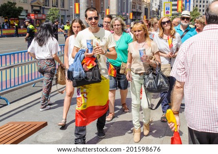 MADRID, SPAIN - JUN 19, 2014: Unidentified Spanish people with national flags walk in the centre of Madrid on a case of the celebration on a day of the inauguration of the New King of Spain Felipe IV