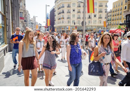 MADRID, SPAIN - JUN 19, 2014: Unidentified Spanish people with multiple national flags walk in Madrid on a case of the celebration on a day of the inauguration of the New King of Spain Felipe IV