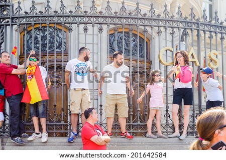 MADRID, SPAIN - JUN 19, 2014: Unidentified Spanish people with national flags on a fence in the centre of Madrid on a case the celebration on a day of the inauguration of the New King of Spain Felipe