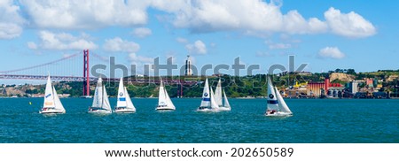 LISBON, PORTUGAL - JUN 20, 2014: Yachts sailing near the Bridge 25 of April in Lisbon, Portugal. It was inaugurated on August 6, 1966