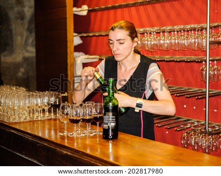 PORTO, PORTUGAL - JUN 21, 2014: Unidentified woman prepares port wine of the Calem trademark for degustation. Calem company was created in 1859 and now it\'s one of the world brands of the port wines