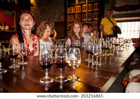 PORTO, PORTUGAL - JUN 21, 2014:  Unidentified tourist tastes the port wine of the Calem trademark. Calem company was created in 1859 and now it\'s one of the world brands of the port wines from Porto