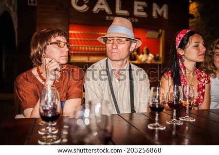 PORTO, PORTUGAL - JUN 21, 2014:  Unidentified tourists taste the port wine of the Calem trademark. Calem company was created in 1859 and now it\'s one of the world brands of the port wines from Porto