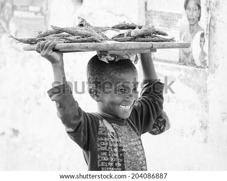 ACCARA, GHANA - MAR 2, 2012: Unidentified Ghanaian boy carries a tray with fish in black and white. People of Ghana suffer of poverty due to the unstable economical situation
